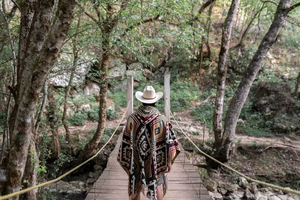 Tanınmayan Meksikalı genç adam panço giyiyor ve tahta bir köprünün üzerinde duruyor. Özgürlük ve macera kavramı