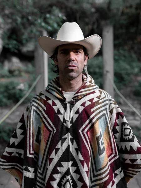 Tahta bir köprüde şapka ve panço giyen Meksikalı bir gencin portresi. Özgürlük ve macera kavramı