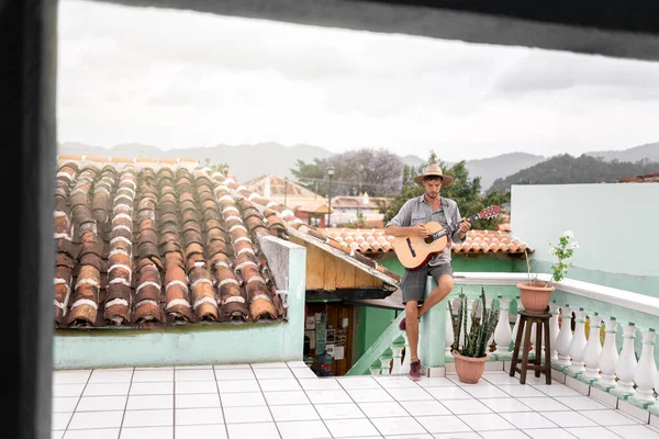 Genç bir adam yaz mevsiminde dışarıda şapka takarak gitar çalışıyor. Müzik sanatçısı gezgini kavramı