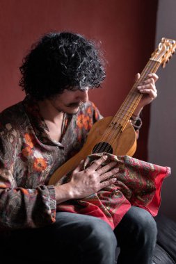 Genç bir Meksikalı müzisyen jarana gitarını temizliyor. Evde müzik besteleme kavramı