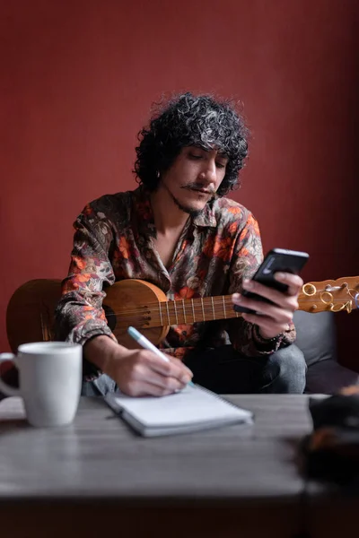 Genç bir Meksikalı müzisyen telefonuyla araştırma yapıyor ve not alıyor. Evde müzik besteleme kavramı