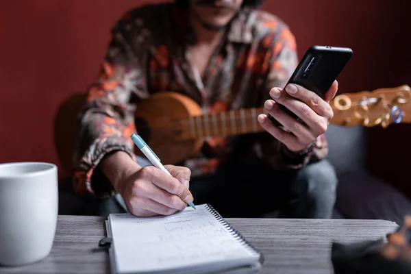 Genç bir Meksikalı müzisyen telefonuyla araştırma yapıyor ve not alıyor. Evde müzik besteleme kavramı