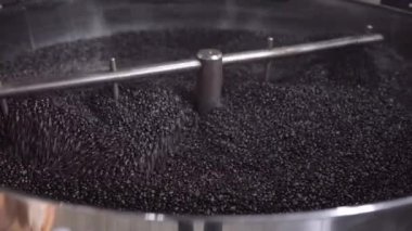 Kavrulmuş kahve taneleri kızartma makinesinin soğutma tepsisinde karıştırılıyor. Yerel kahve üretimi kavramı