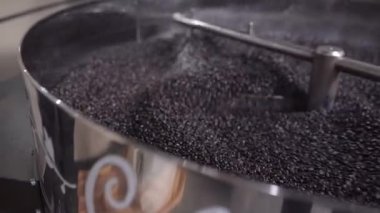 Kavrulmuş kahve taneleri kızartma makinesinin soğutma tepsisinde karıştırılıyor. Yerel kahve üretimi kavramı
