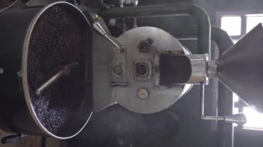 Kavrulmuş kahve taneleri kızartma makinesinin soğutma tepsisinde karıştırılıyor. Yerel kahve üretimi kavramı