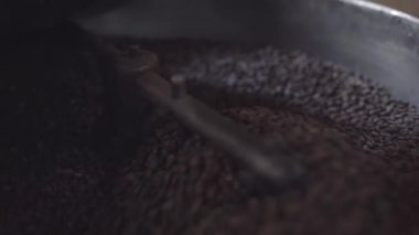 Kavrulmuş kahve taneleri kızartma makinesinin soğutma tepsisinde karıştırılıyor. Yerel kahve üretimi kavramı
