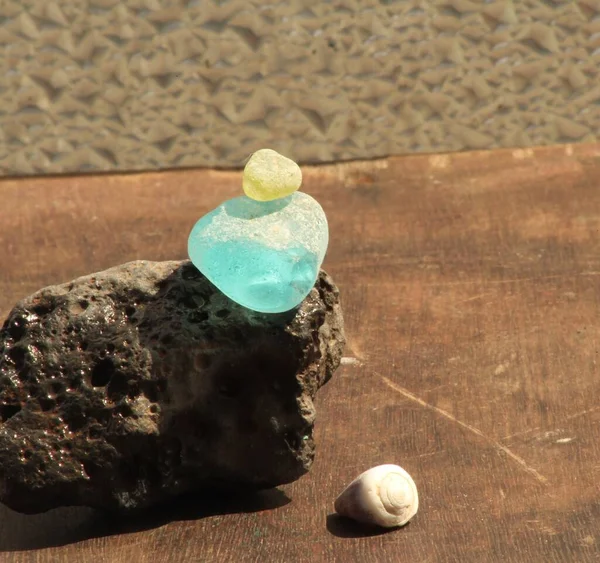 不同颜色的海玻璃卵石在熔岩石上保持平衡 放在木板上 — 图库照片