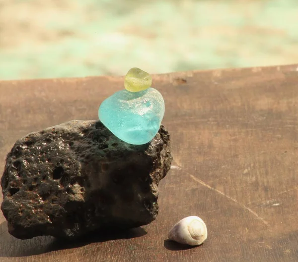 不同颜色的海玻璃卵石在熔岩石上保持平衡 放在木板上 — 图库照片