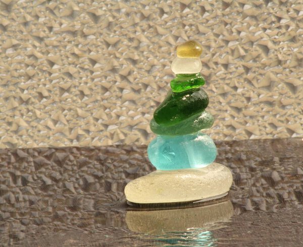 Different colours of sea glass pebbles balances on a wood plank