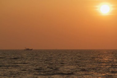 view from seashore during a clear sunset with some boats in the horizon