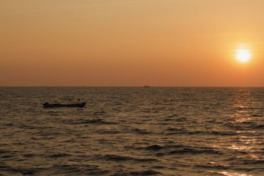 view from seashore during a clear sunset with some boats in the horizon