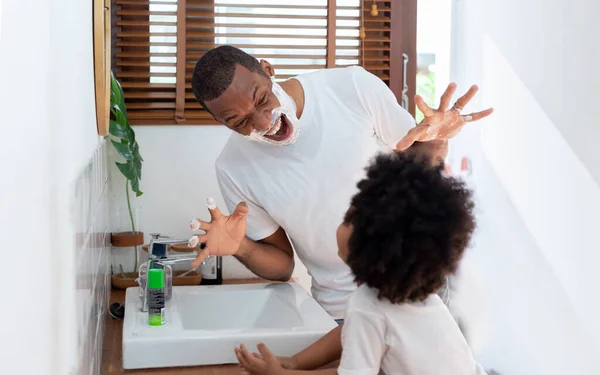 美国黑人父亲和小男孩在家里的浴室里一起玩剃须泡沫游戏 黑人家庭玩得很开心 — 图库照片