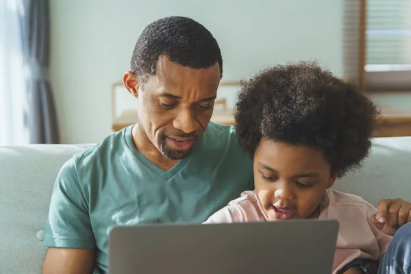 用笔记本电脑微笑非裔美国人的父亲和他可爱的儿子 — 图库照片