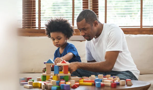 非洲父亲和男孩在家里沙发上玩五彩缤纷的木块玩具 — 图库照片