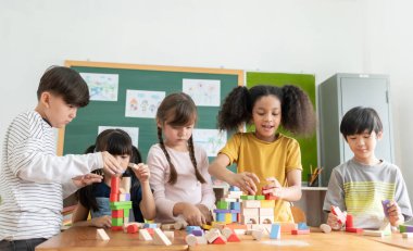 Group Of Multi ethnic Elementary School Pupils playing wooden block toys in Classroom together, Indoor activity.