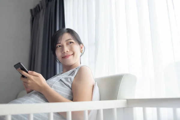 Jovem Coreana Grávida Sorrindo Sentado Cama Usando Telefone Celular Casa — Fotografia de Stock