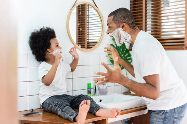 Alegre Padre Afroamericano Pequeño Hijo Riendo Jugando Espuma Afeitar Sus — Foto de Stock