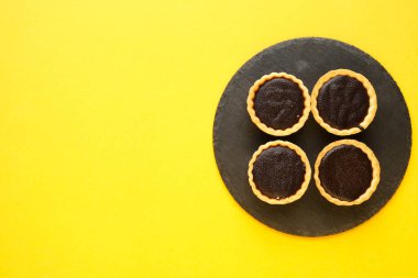 Tahta levhada 4 çikolatalı tart resmi ve sarı telif alanı arka planı. Tatlı olarak yemek hazır..