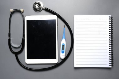 Tıbbi danışmanlık kavramı için stetoskop, termometre ve defter içeren bir sekme resmi.
