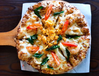 Flatlay picture of seafood salted egg pizza serve on the table.