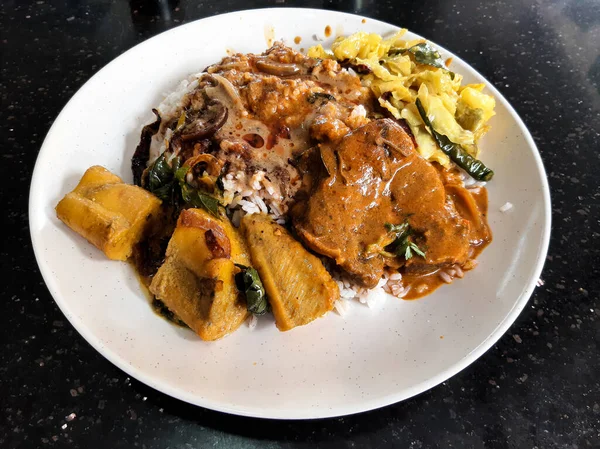 Selective focus picture of nasi kandar consist of curry mutton, squid egg and vegetable insight