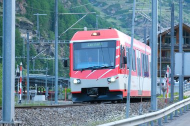 Hareket bulanıklığı olan seçici odak resmi ve Zermatt tren istasyonundan ayrılırken kırmızı trenin ses efekti.