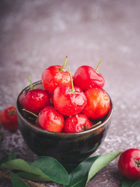 Taş zeminde yaprakları olan bir seramik kasede olgun kırmızı kirazlar. Mesaj için yer var. Tatlı organik meyveler. Sağlıklı meyve kavramı