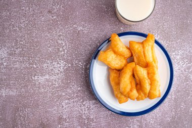 Bol yağda kızartılmış hamur çubukları ya da beyaz tabakta Çin çöreği çubukları ve gri taştan arka planda bir bardak soya sütü. Metin için boşluk