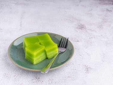 Tabakta tatlı pasta (veya khanom Chan) ve gri taş zemin üzerinde küçük çatal. Mesaj için yer var. Tayland tatlısı. Seçici odaklanma. Rahatlama zamanı. Tatlı kavramı