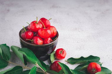 Tahta bir masada yapraklarla seramik bir tabakta olgun kırmızı kirazlar. Mesaj için yer var. Tatlı organik meyveler. Sağlıklı meyve kavramı.