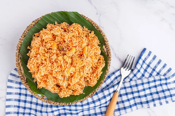 Sweet and sour crispy noodles or Mee krob in the Thai language on a dish with cutlery and cloth placed on marble background. Top view with copy space for text.