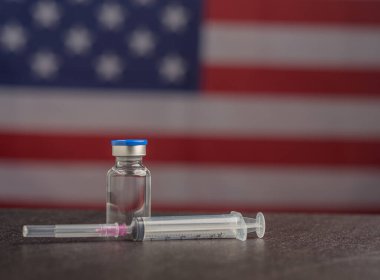 Aşı şişesi ve Amerikan bayraklı şırınga. Bağışıklık aşısı ve virüs enfeksiyonuna karşı tedavi. Yakın plan fotoğraf. Tıbbi ve sağlık hizmetleri kavramı.