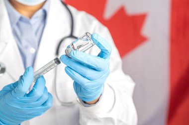 Bir doktor Kanada bayrağının arka planına karşı aşı hazırlar. Bağışıklık aşısı ve virüs enfeksiyonuna karşı tedavi. Tıbbi konsept ve virüse karşı savaş.