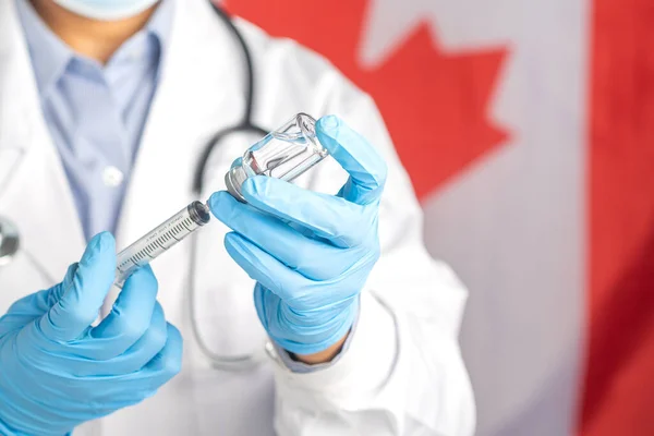 Bir doktor Kanada bayrağının arka planına karşı aşı hazırlar. Bağışıklık aşısı ve virüs enfeksiyonuna karşı tedavi. Tıbbi konsept ve virüse karşı savaş.