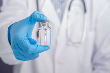 Gri arka planda aşı şişesi olan bir doktorun göbeğinde. Bağışıklık aşısı ve virüs enfeksiyonuna karşı tedavi. Tıbbi konsept ve virüse karşı savaş.