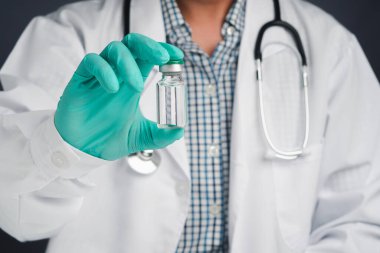 Aşı şişesi tutan bir doktor. Bağışıklık aşısı ve virüs enfeksiyonuna karşı tedavi. Ön manzara. Tıbbi konsept ve virüse karşı savaş.