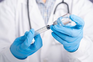 Beyaz üniformalı bir doktor, şırınga tutan tıbbi eldivenler ve aşı için aşı şişesi. Bağışıklık aşısı ve koronavirüs enfeksiyonu tedavisi.