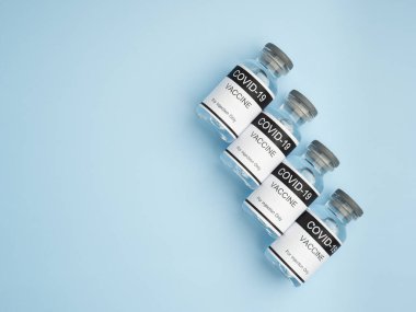 Açık mavi arka planda, COVID-19 aşısının önleme, aşılama ve koronavirüs enfeksiyonu tedavisi için cam şişelerde üst görüntüsü. Mesaj için yer var. Tıbbi ve aşı kavramı.