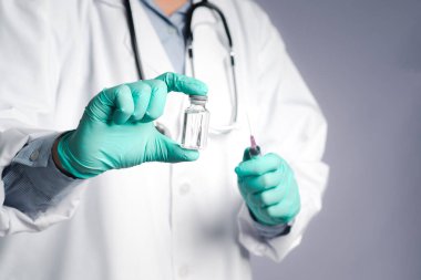 Elinde şırınga ve COVID-19 aşı şişesi olan bir doktor. Bağışıklık aşısı ve koronavirüs enfeksiyonunun tedavisi. Ön manzara. Tıbbi konsept ve koronavirüsle mücadele.