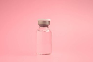 Açık pembe arka planda cam bir şişedeki aşı. Bağışıklık aşısı ve virüs enfeksiyonuna karşı tedavi. Yan görüş. Tıbbi ve sağlık hizmetleri kavramı.