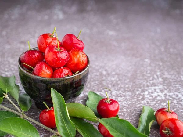 Seramik bir kasede olgun kırmızı kirazlar ve arka planda yapraklar. Mesaj için yer var. Sağlık meyveleri kavramı.