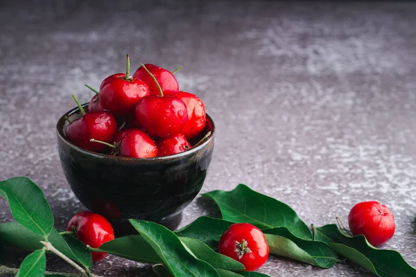 Seramik bir kasede olgun kırmızı kirazlar ve arka planda yapraklar. Mesaj için yer var. Tatlı organik meyveler. Sağlıklı meyve kavramı.