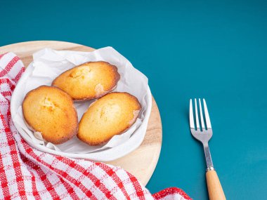 Mavi ışık arka planına yerleştirilmiş bir tabakta limon jöleli kurabiyeler. Madeleine - ev yapımı geleneksel Fransız küçük kurabiyesi. Deniz kabuğu tatlı kekleri.