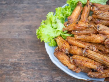 Fried chicken wings with fish sauce with salad vegetables on a white plate placed on a wooden table. Close-up photo. Space for text. Concept of foods.