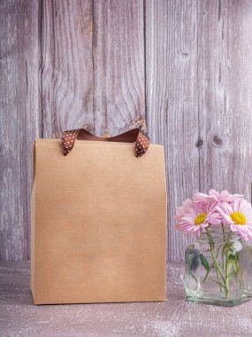 Kese kağıdı ambalajında, tahta bir duvarla gri bir arka plana kurdele sapları yerleştirilmiş. Metin için kopyalama alanı olan yan görünüm.