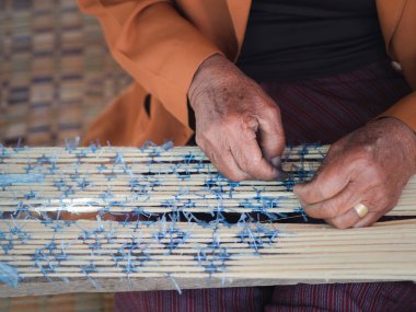 Close-up photo of hands senior woman holding straw rope to make a mat.