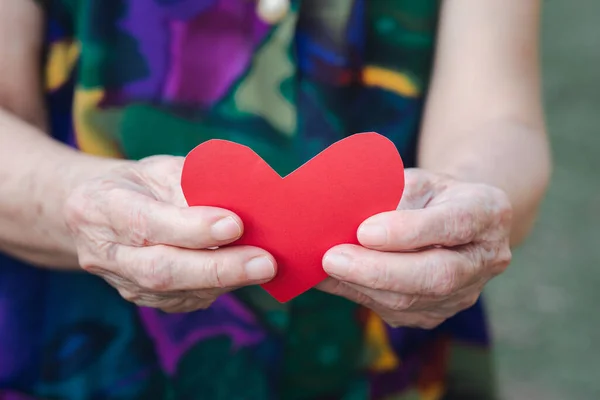 红纸切割心脏的形状由资深女子手托着 情人节 老年人与爱情的概念 — 图库照片