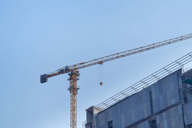 Construction site with the crane on sky background. Big yellow machinery construction crane tool of building industry for heavy lifting. Business engineering equipment modern.