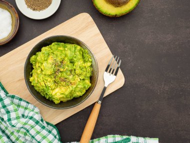 Avokado, limon, tuz ve biber gibi ev yapımı guacamole malzemeleriyle ahşap bir tahtanın üzerine konmuş taze guacamole. Üst Manzara. Geleneksel Meksika hazırlığı kavramı.