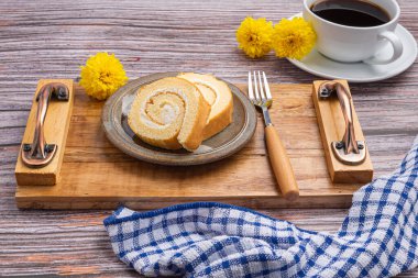 Tahta bir tepside, bir tepside, beyaz bir kahve fincanı ve ahşap bir masanın üzerine yerleştirilmiş yuvarlak kekin en üst görüntüsü. Mesaj için yer var. Rahatlama kavramı.
